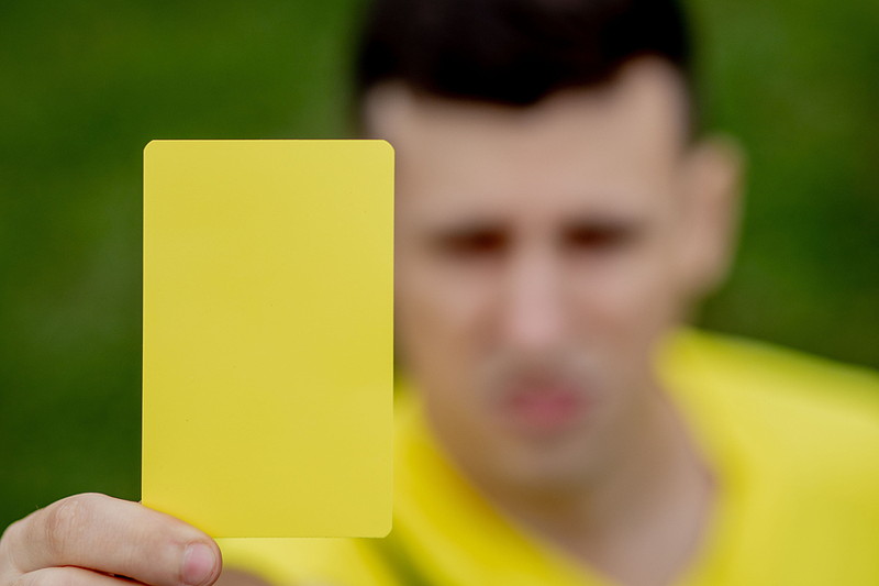 yellow card held up by referee blurred in background