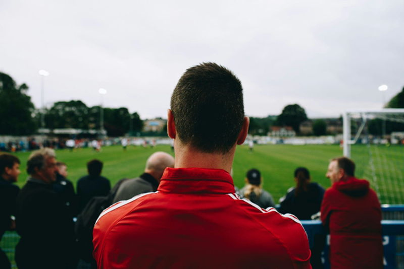 view from behind man watching match at a football stadium