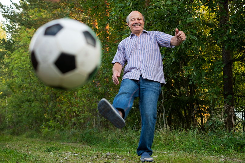 old man kicking a football