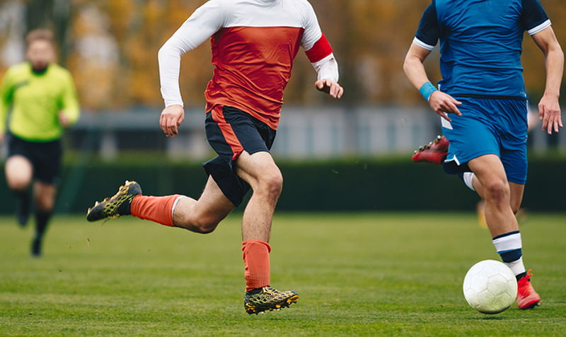 adult football match two players chasing the ball zoomed in