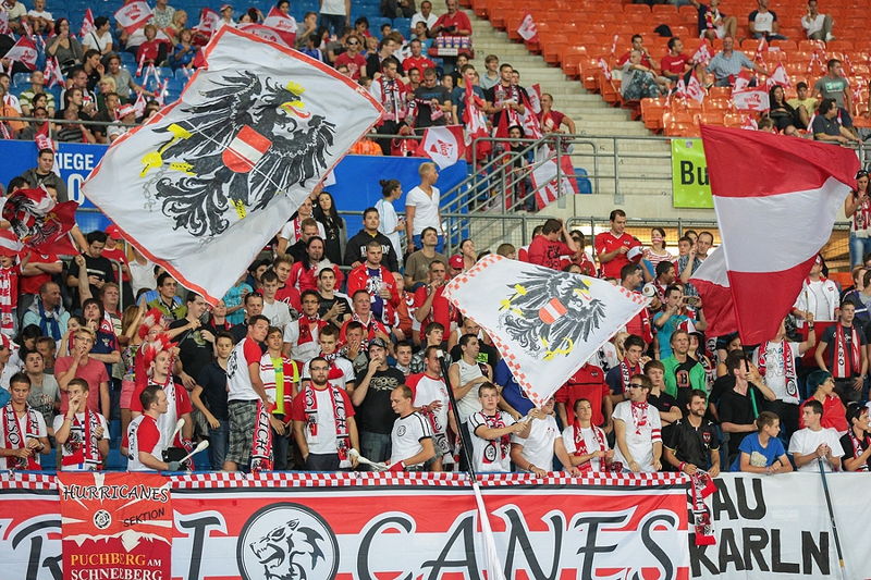 austria fans celebrating and waving flags in stands