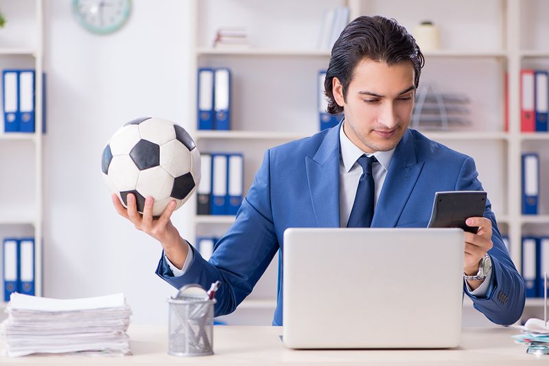 business man in front of laptop holding phone and football transfer window